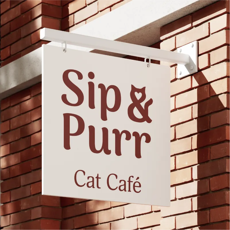 Outdoor hanging signage for Sip & Purr cat café featuring the feline-inspired logo against a red brick wall.