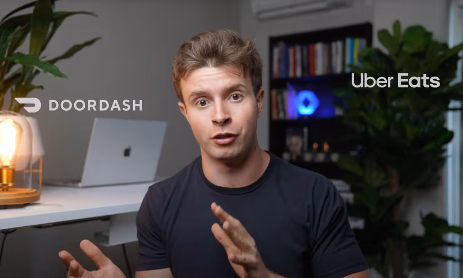 Young man speaking in front of a desk with a laptop, with DoorDash and Uber Eats logos on either side.