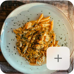 Plate of penne pasta in creamy mushroom sauce garnished with chopped herbs on a wooden table.