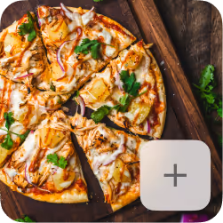 Thin pizza with cheese, pineapple, red onion, and cilantro on a wooden surface, with one slice slightly separated.