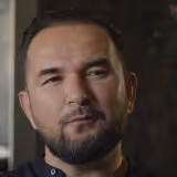 Portrait of a man with a beard and mustache looking slightly to the side with a thoughtful expression.