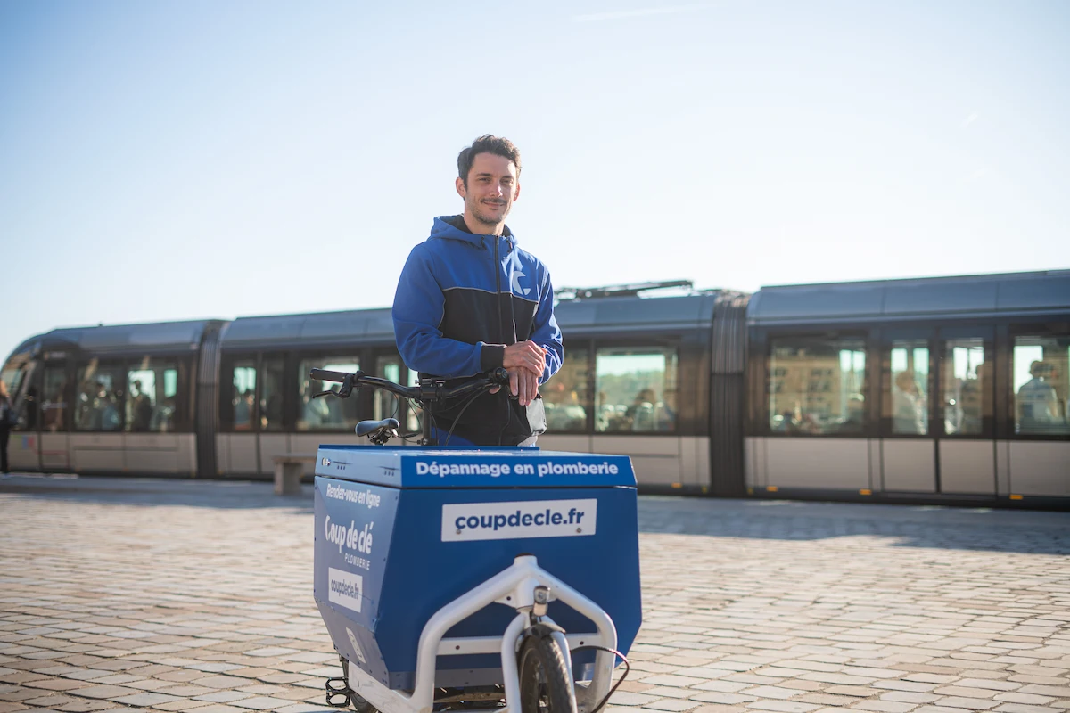 Gros plan sur un vélo cargo de plomberie écologique à Bordeaux, avec un tramway en arrière-plan
