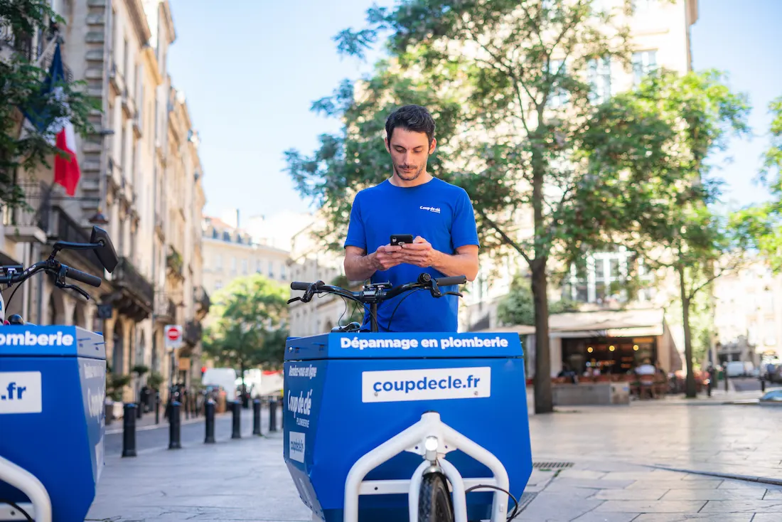 Technicien plombier en uniforme consultant son planning ou la localisation de son intervention sur son téléphone mobile