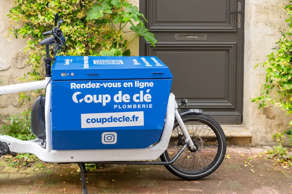 personne marchant à côté d'un vélo en plein air devant l'entrée d'une maison