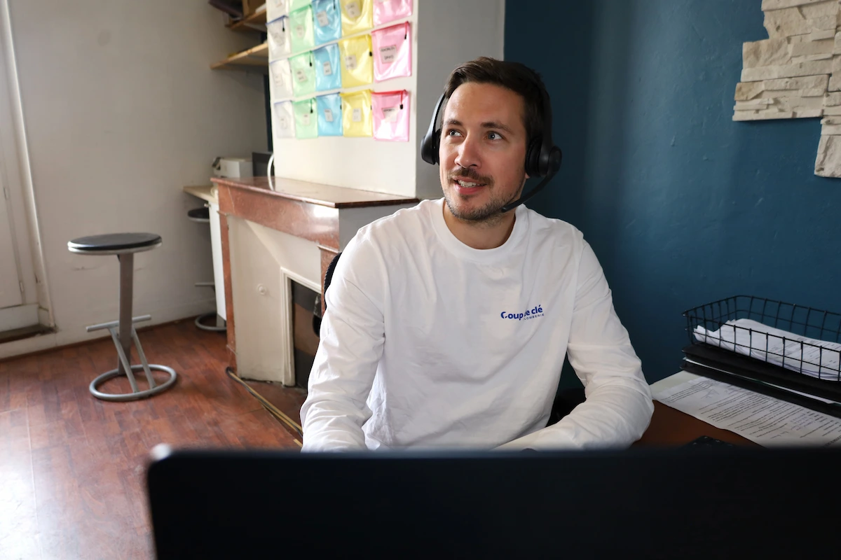 Homme portant un casque avec micro, assis devant un ordinateur dans un bureau.