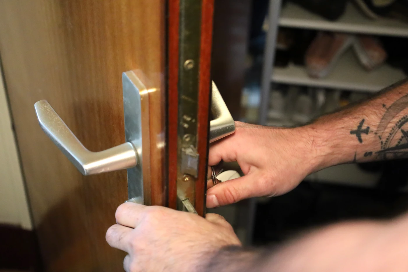 Deux mains tournant une clé dans la serrure d'une porte en bois partiellement ouverte à Bordeaux.