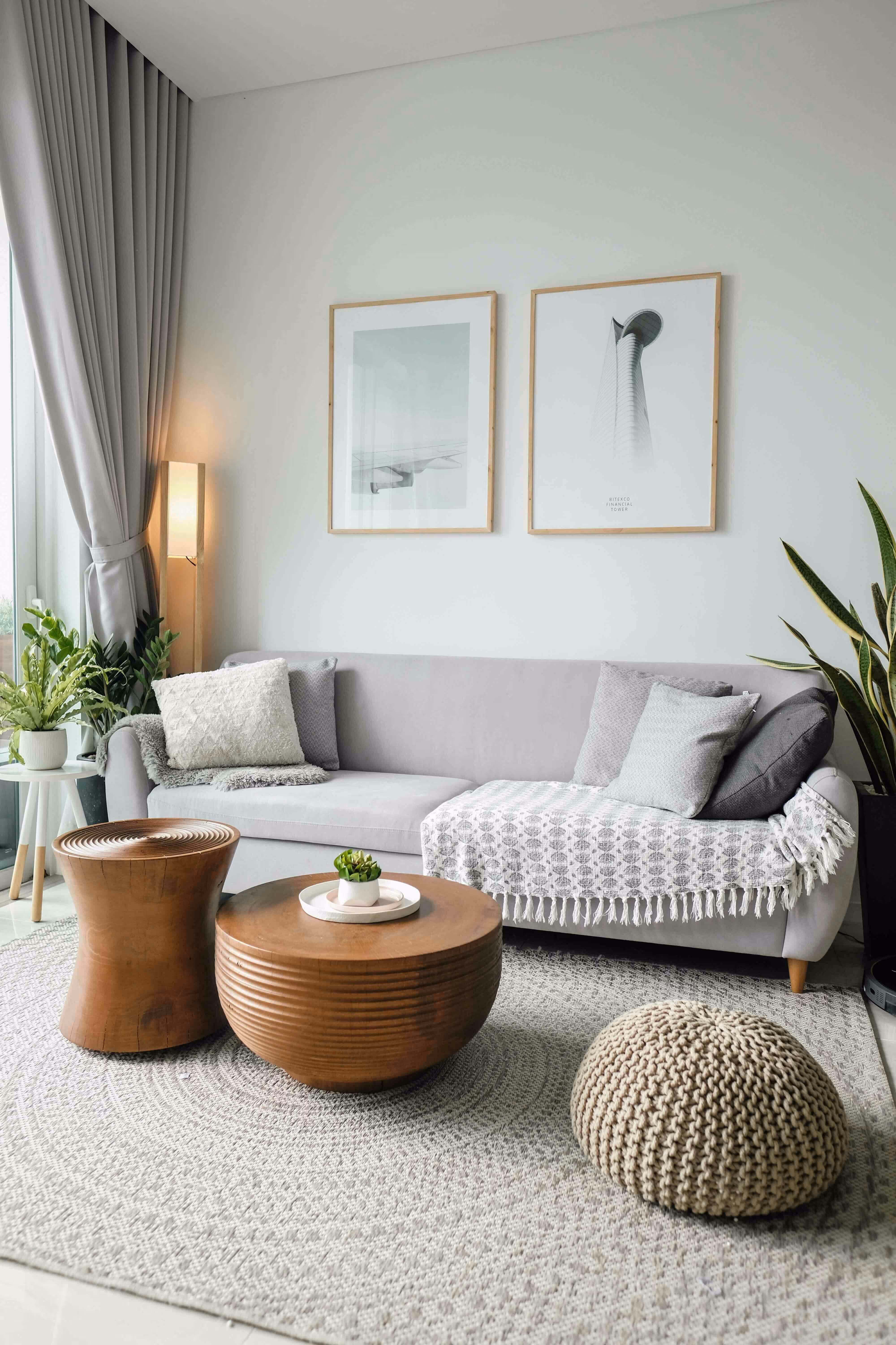 Living room with a grey sofa, brown coffee tables and plants.