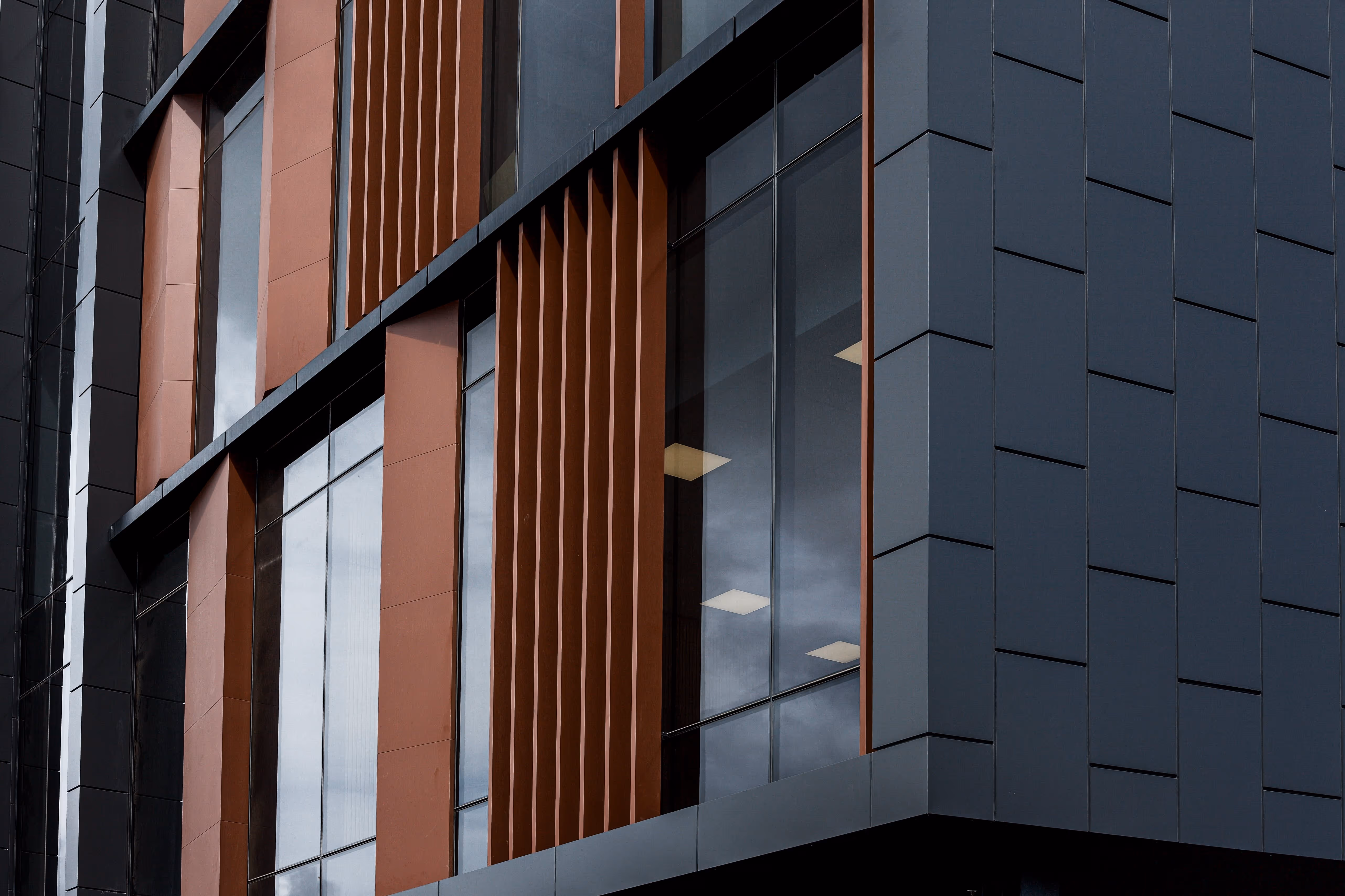 Close-up of a modern building exterior showcasing architectural facade, large windows, and sleek external shades.