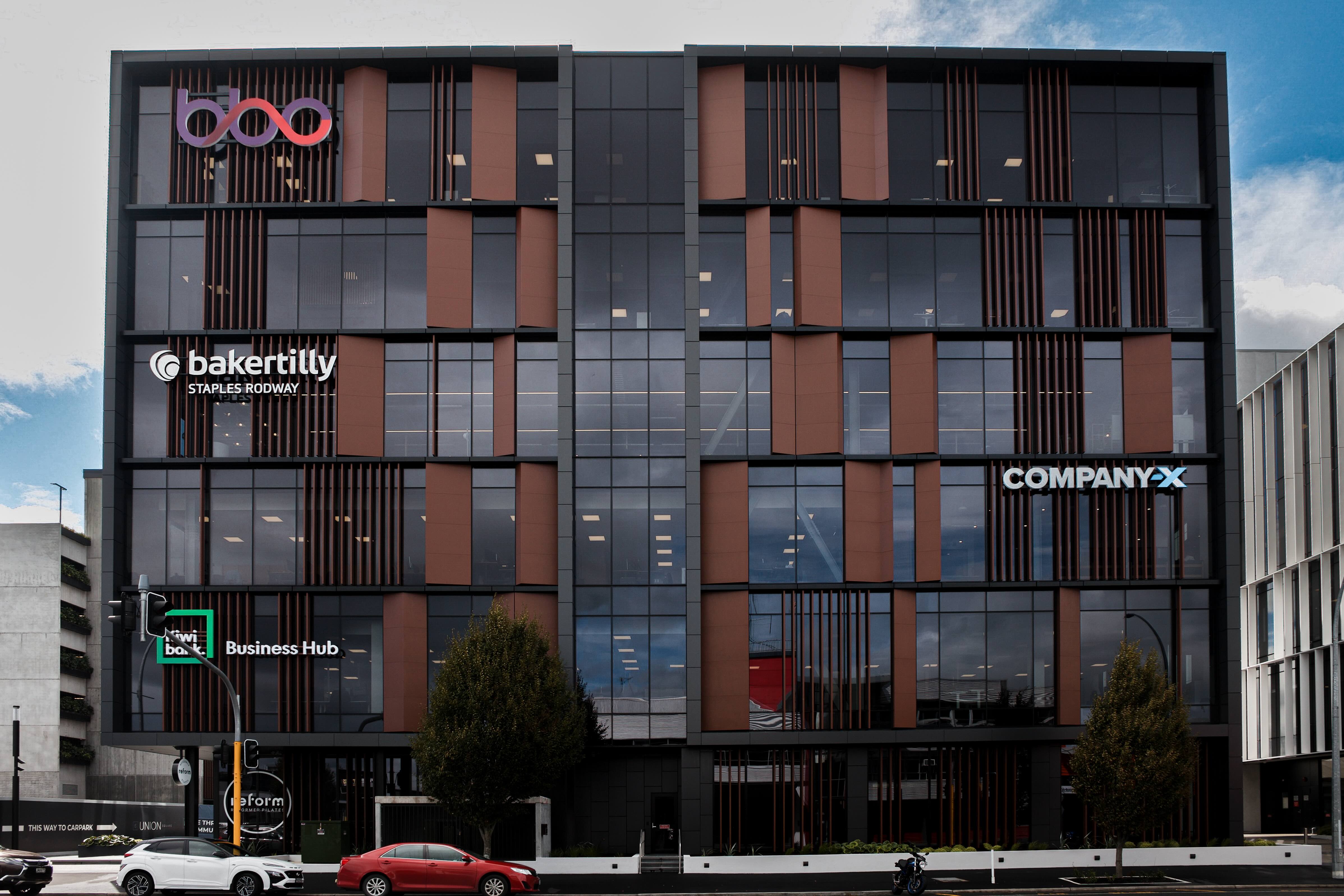 Union Square Office Development, Building E – A modern commercial building in Hamilton, New Zealand, featuring a dynamic façade of terracotta-toned panels, vertical fins, and large glass sections.