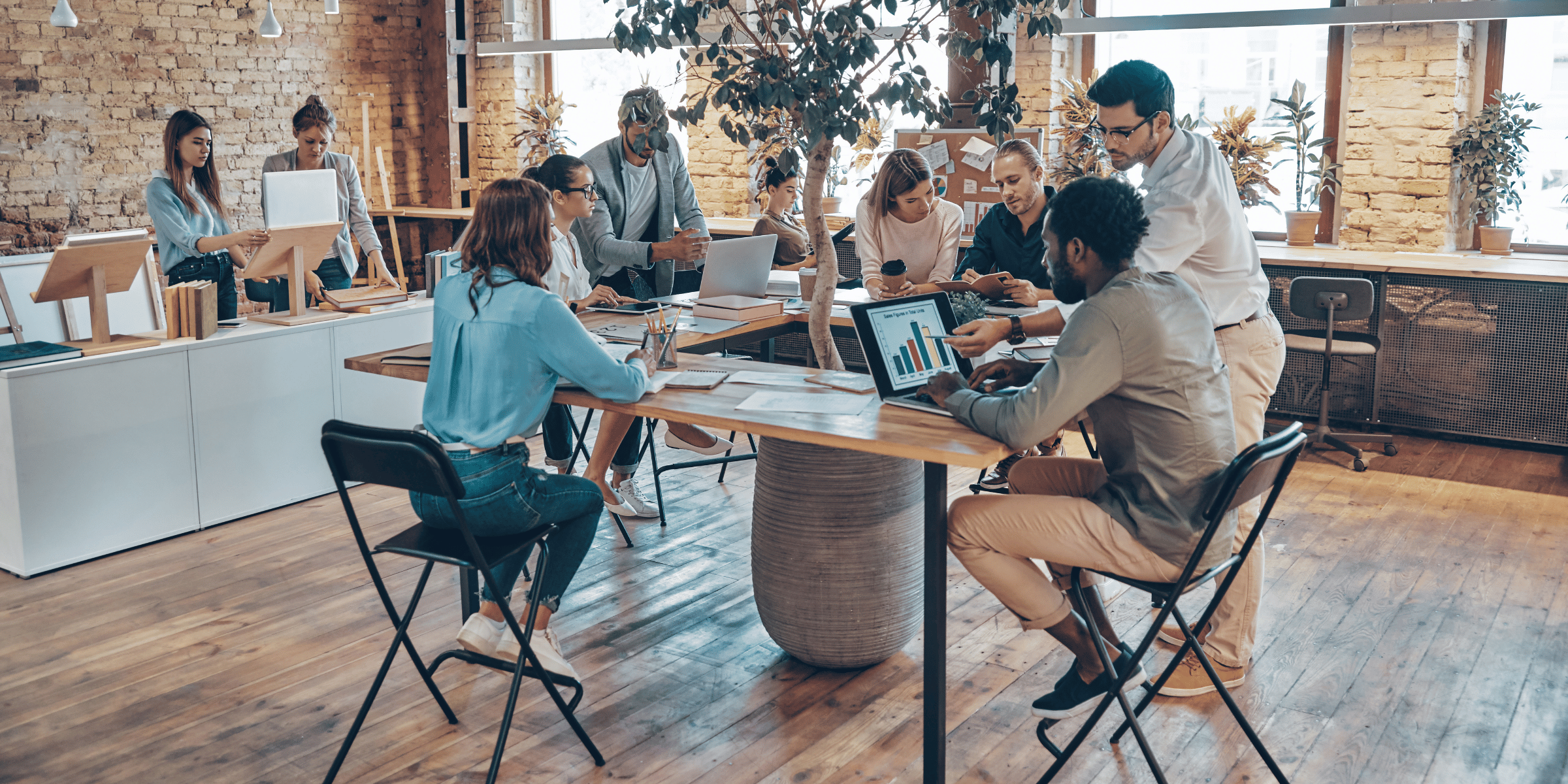 Modernes, freundliches Büro mit einigen jungen Menschen, die in entspannter Atmosphäre an Bildschirmen arbeiten. 