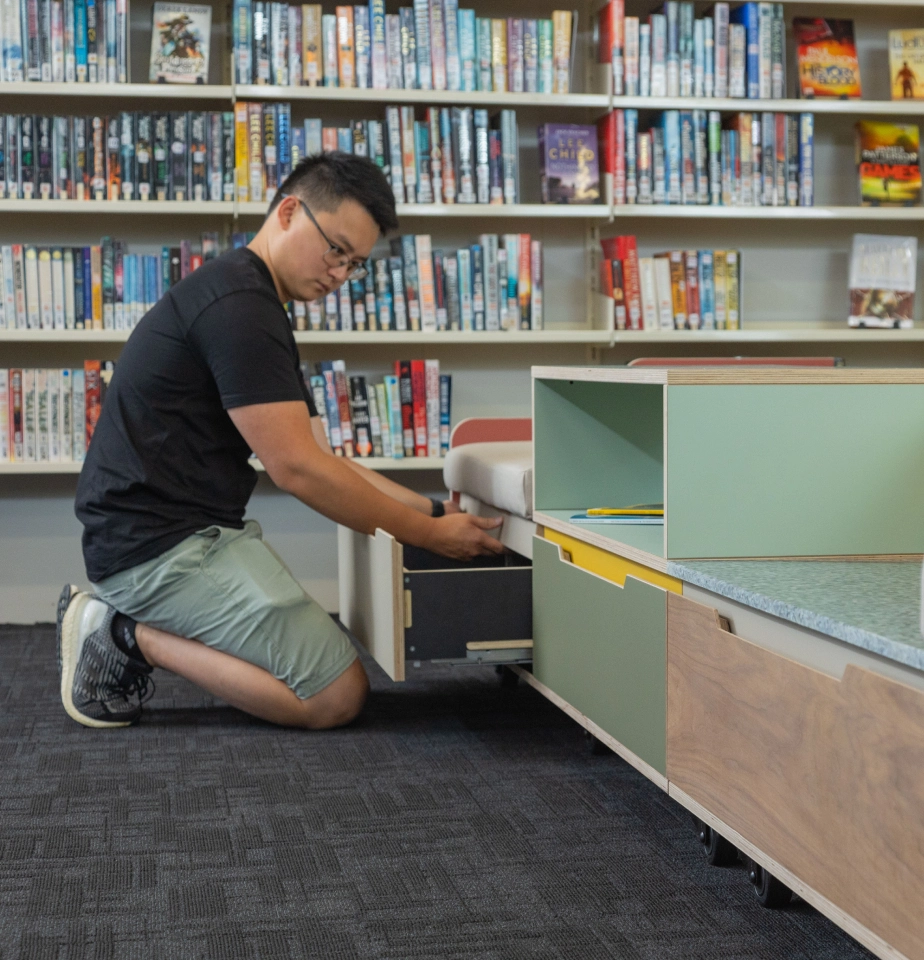 Worker assembling a set of UD modular furniture drawers in a library
