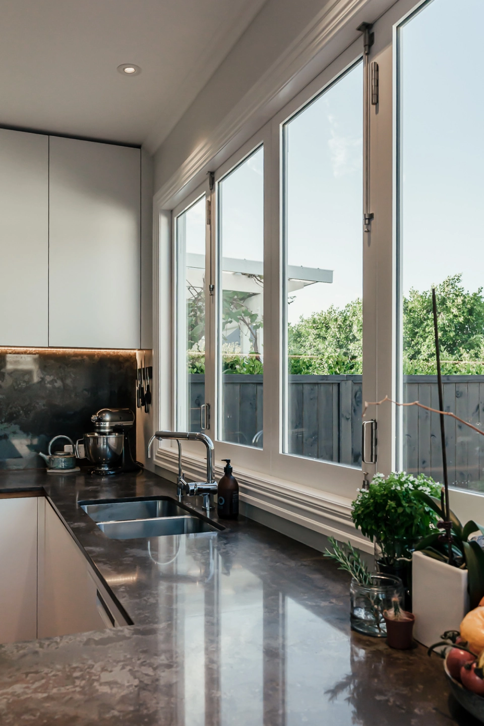 Modern kitchen features frameless windows that offer a view of the outdoors.