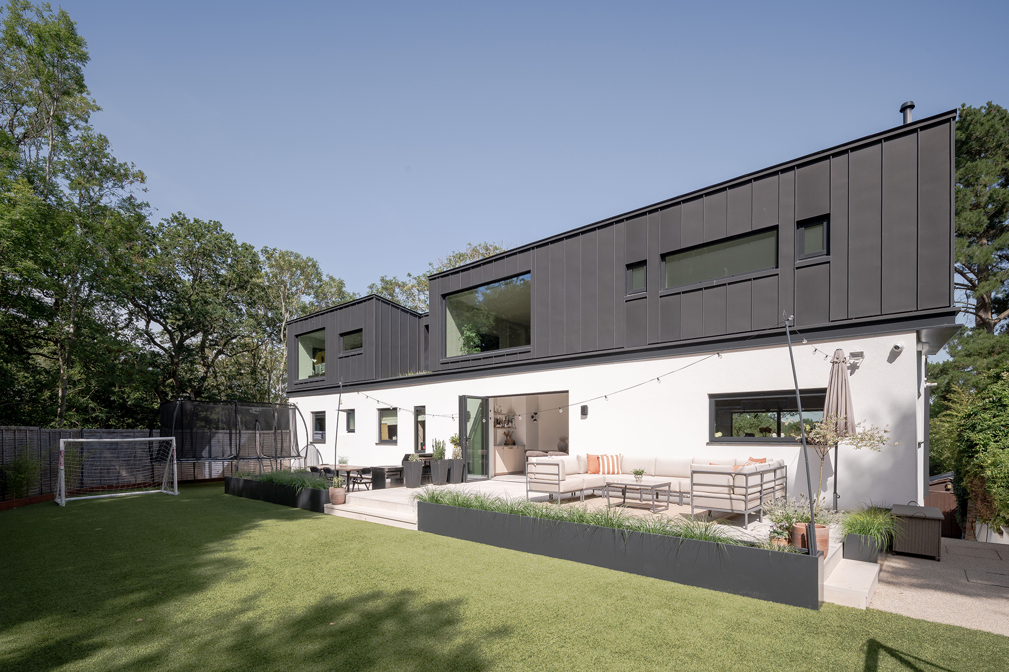 rear image of contemporary upgraded home with feature zinc cladding, with feature roof terrace and white render 