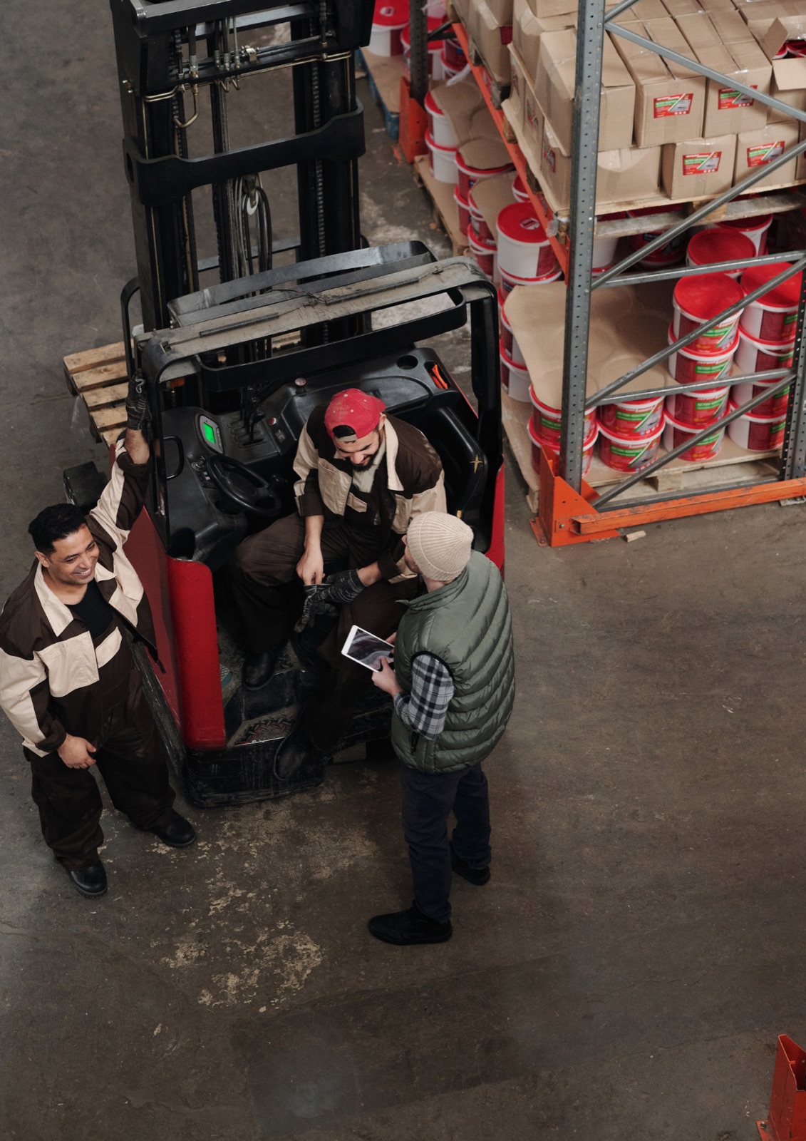 Warehouse team members talking beside a forklift