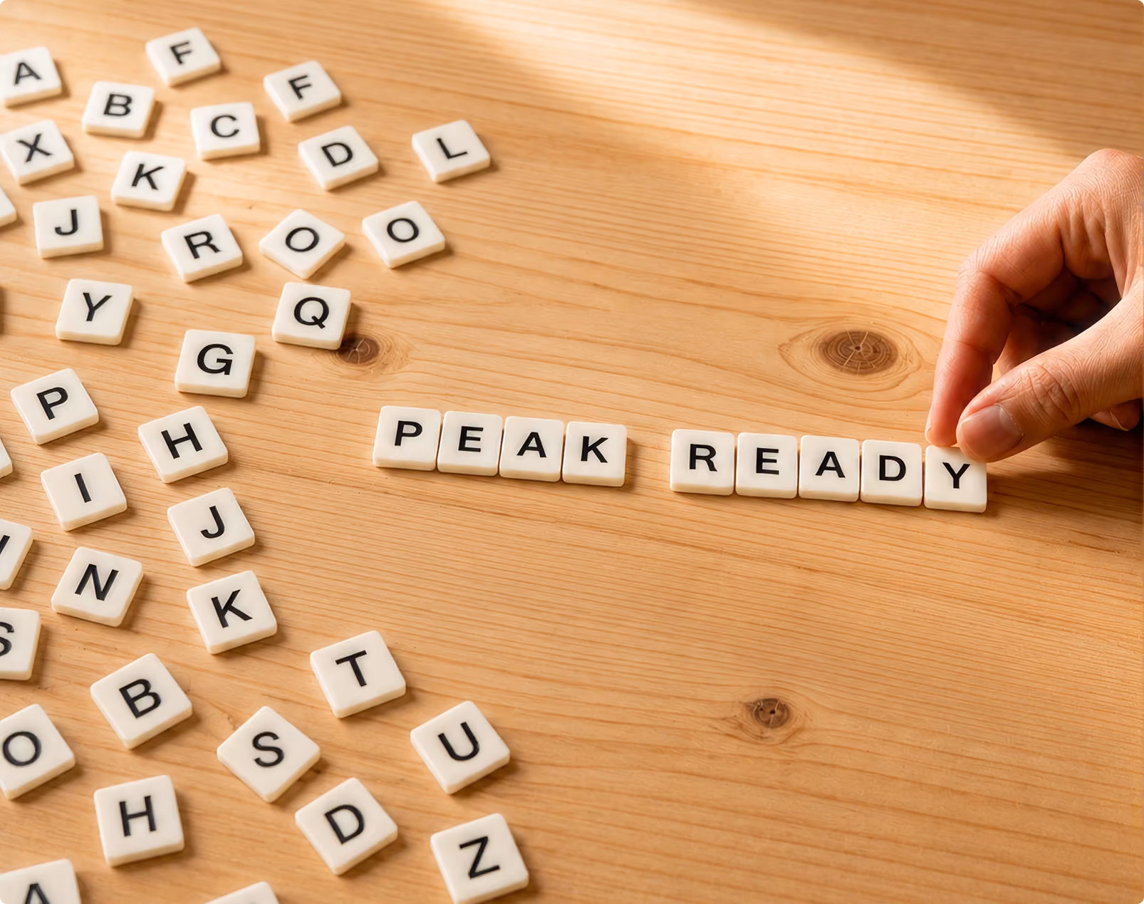 Scrabble letters on a table with hand building letters "Peak Ready"
