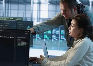 IT engineers monitoring systems on several screens