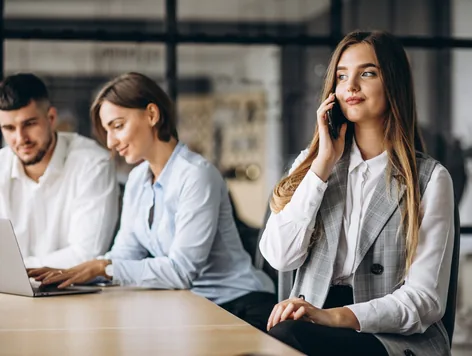 Team working at a shared table while a colleague takes a call
