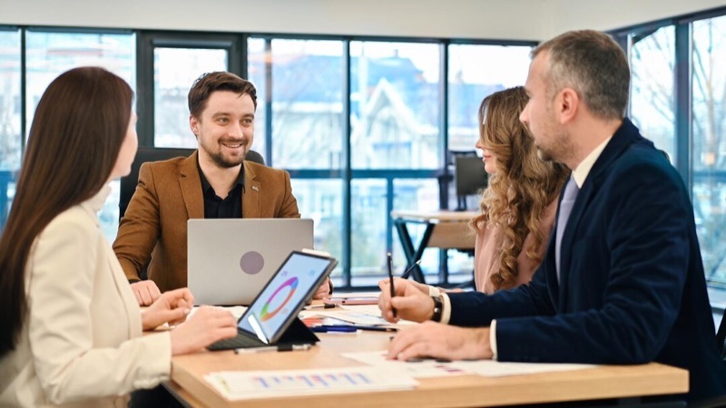 Team working at a shared table while a colleague takes a call
