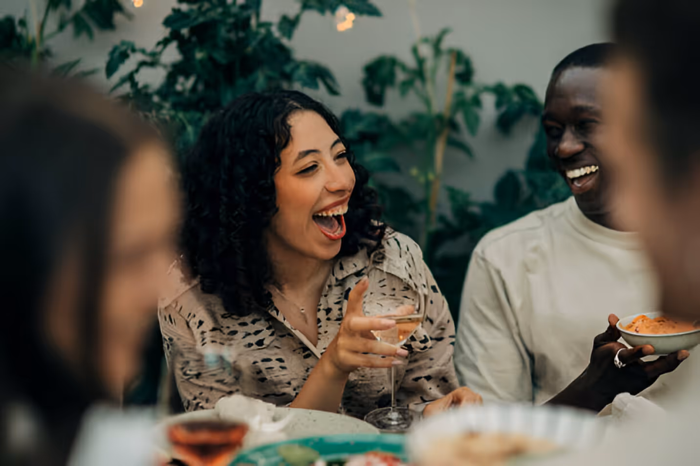 A group of people laughing at a dinner table.