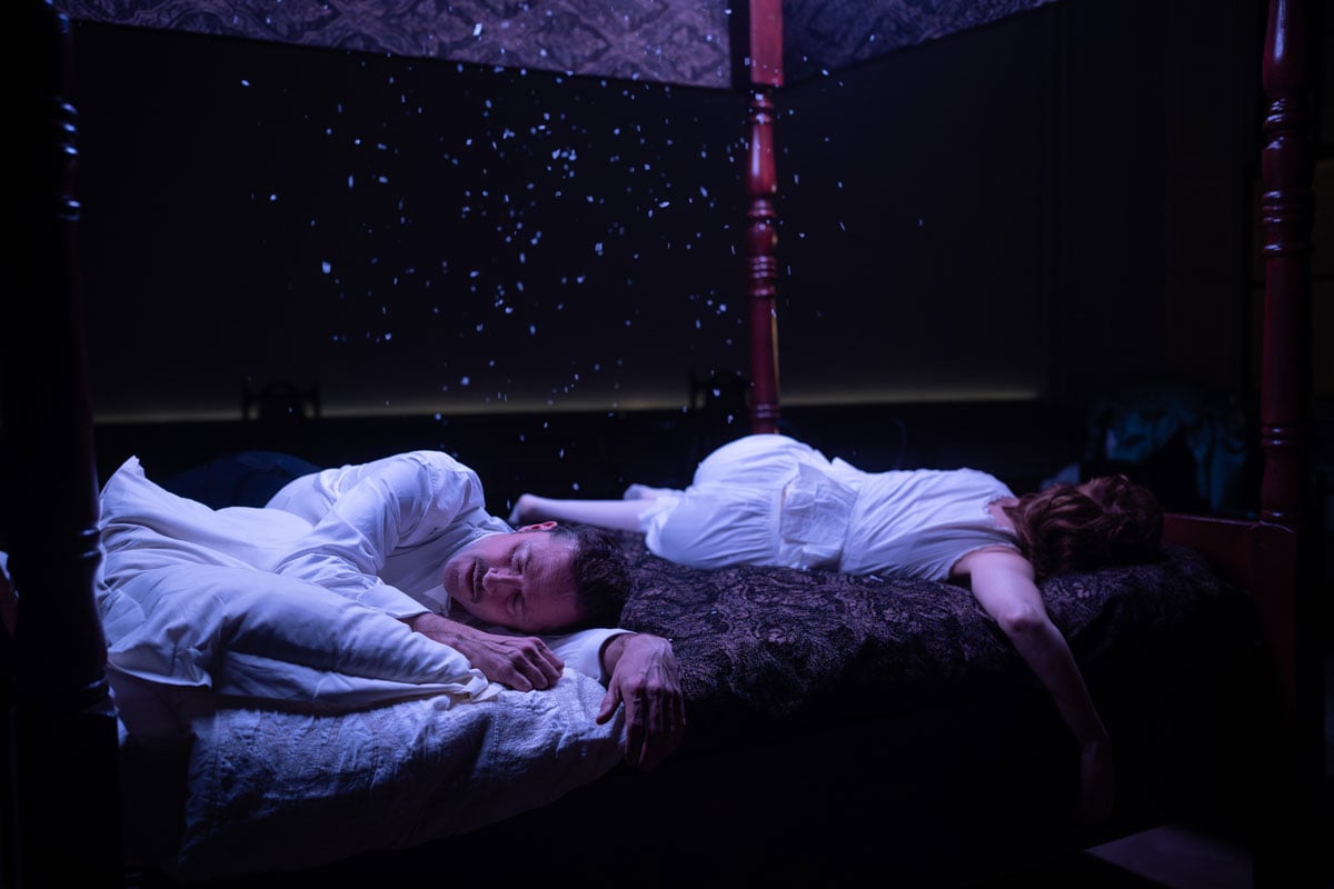 two people asleep on bed, feathers falling from the canopy