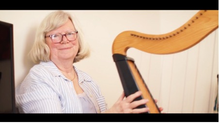 A person playing a harp in a white room. Filmed for a Homes England video case study.