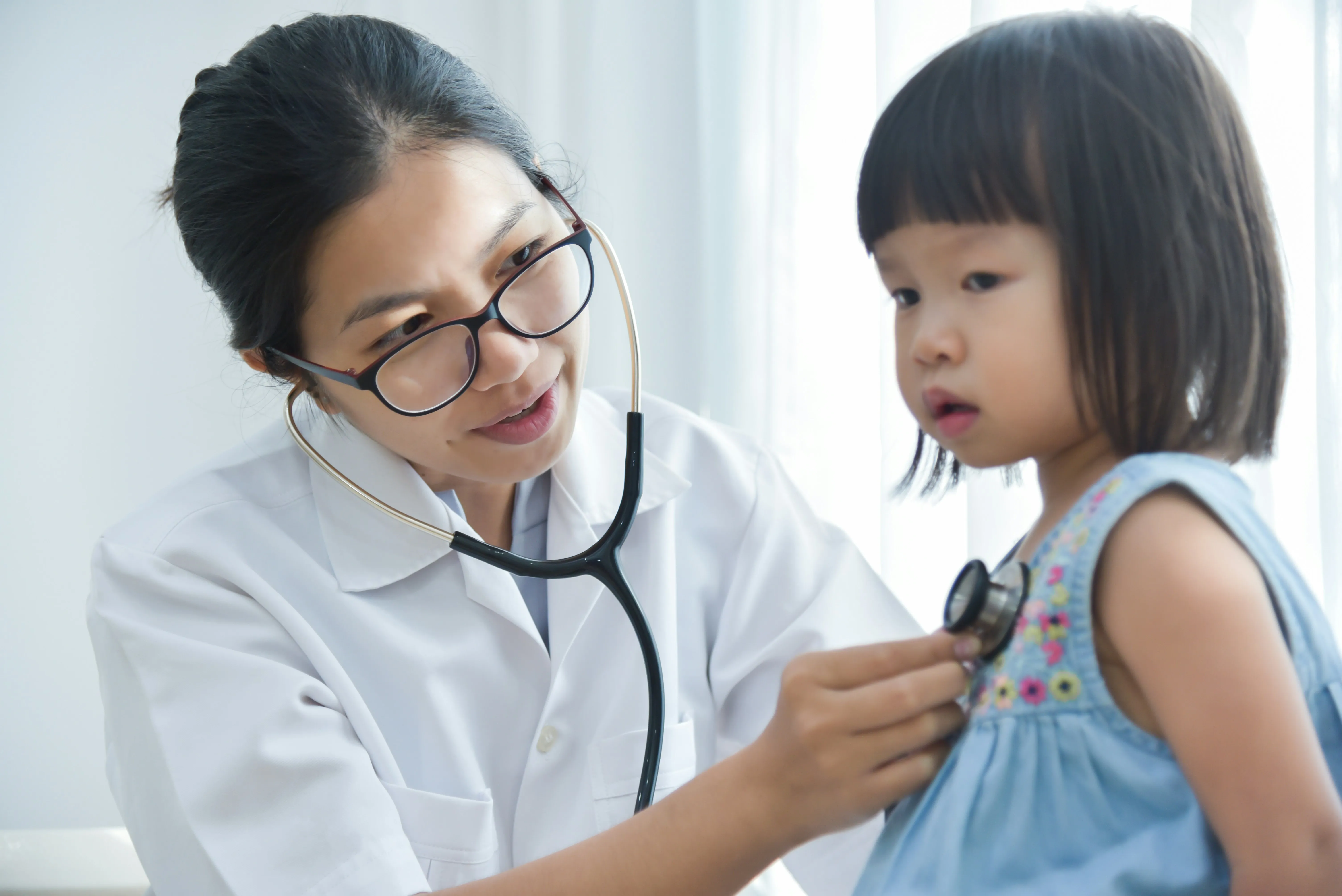 Doctor using a stethoscope to check a young girl’s chest.
