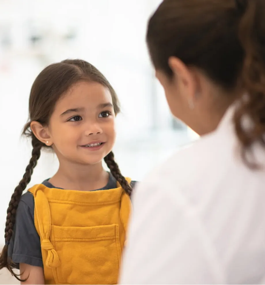 Young girl with braided hair smiling at an adult.