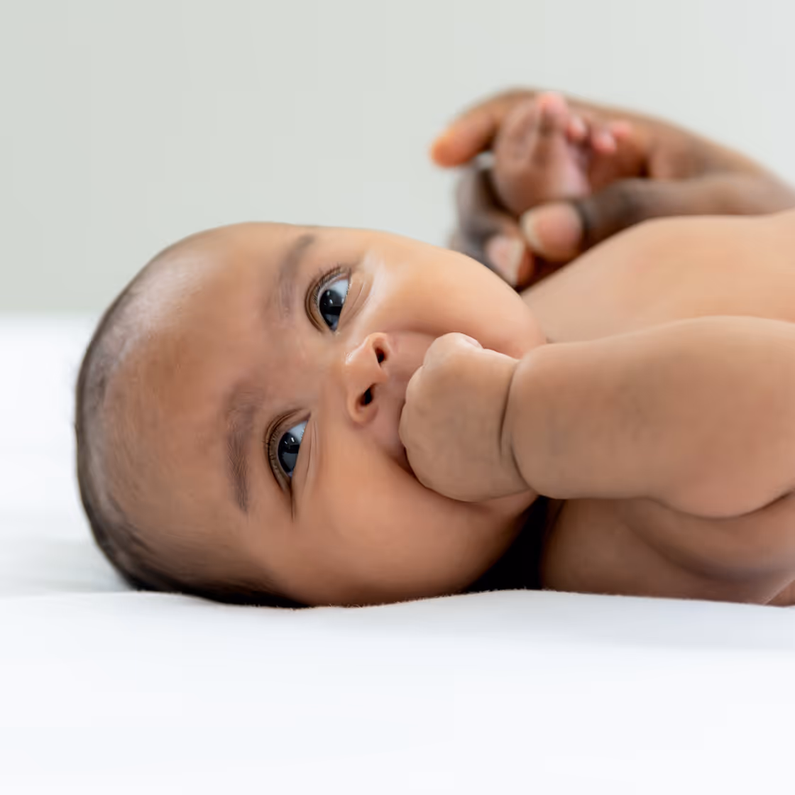 Baby lying on its back and staring curiously into the distance.