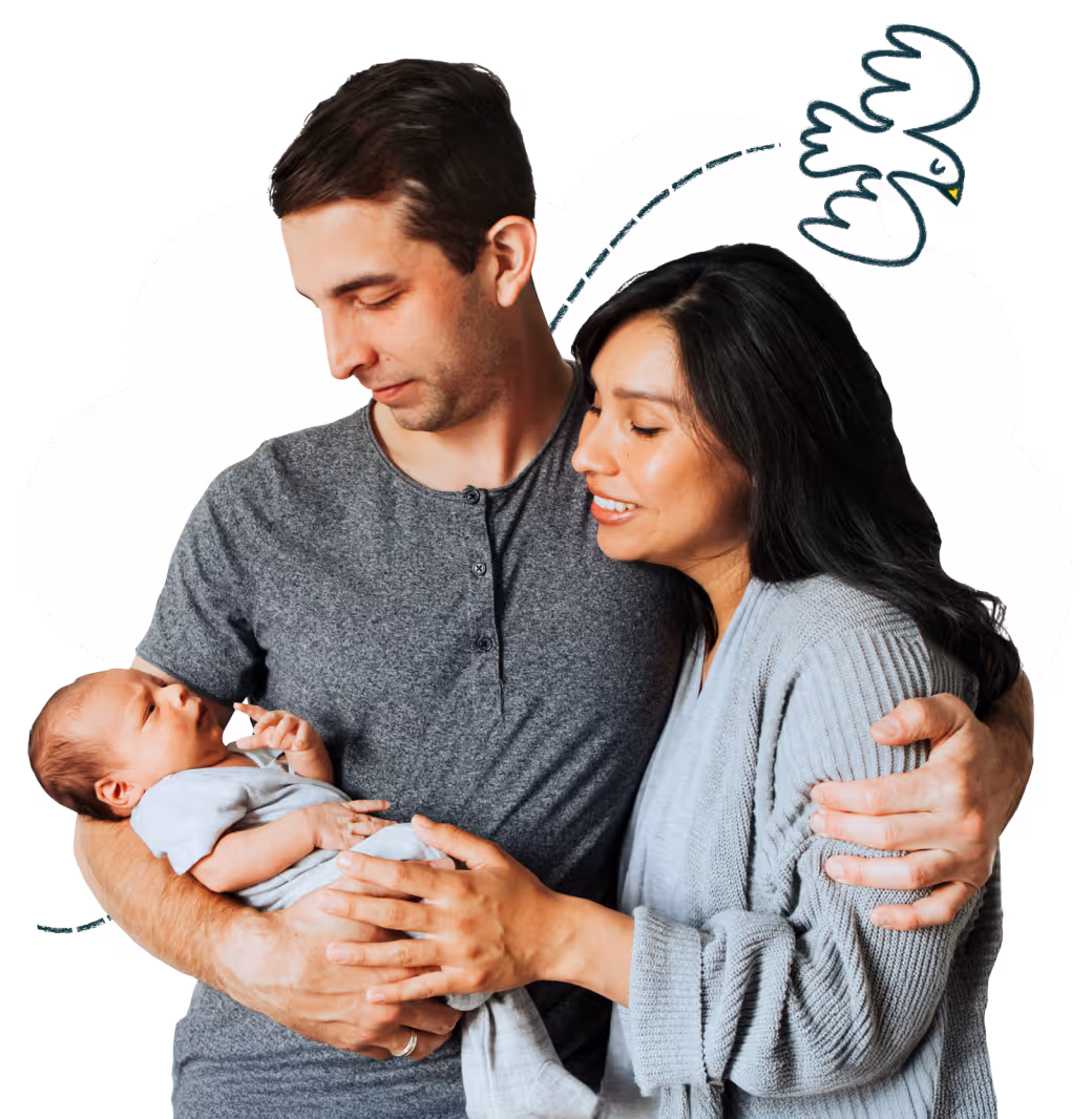Parents gently holding their newborn baby together and looking lovingly at it.