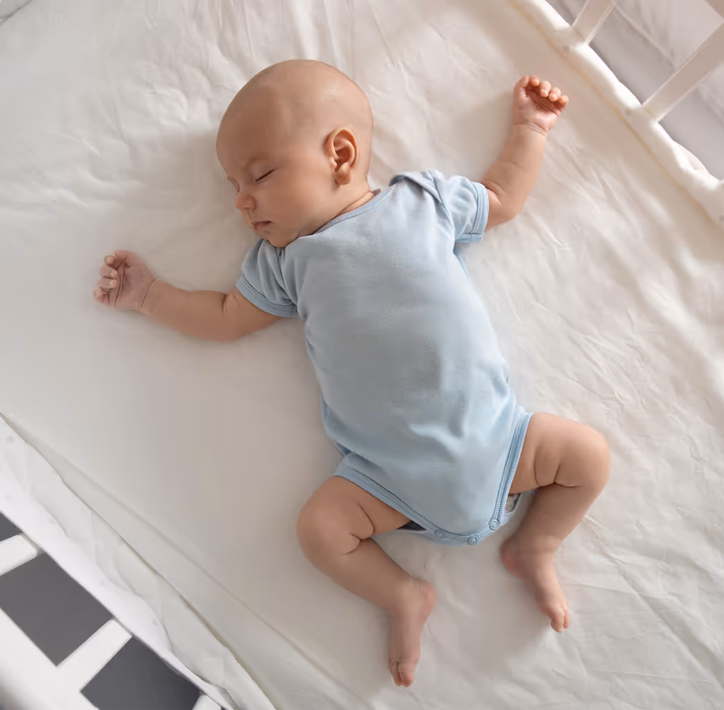 Baby sleeping calmly on its back in a crib.