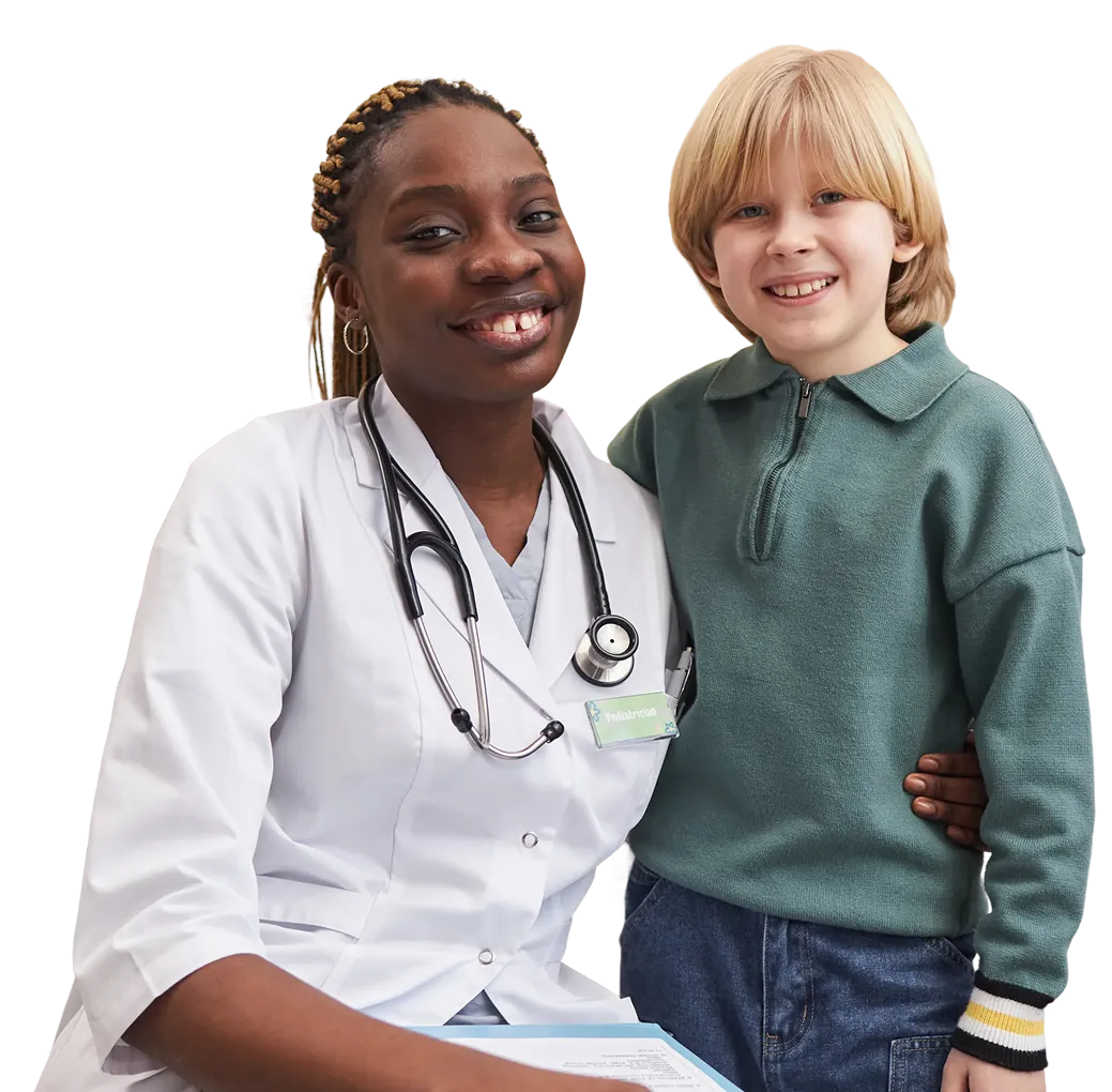Smiling female doctor in white coat with stethoscope hugging a happy young boy in a green sweater.