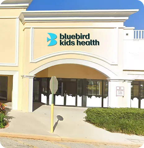 Entrance of a beige building with a bluebird logo and the text 'bluebird kids health' above the doorway.