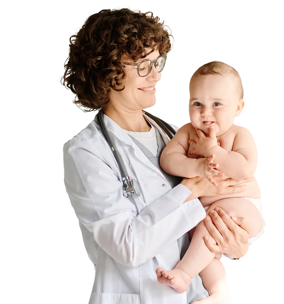 Smiling female doctor with curly hair and glasses holding a happy baby in her arms.