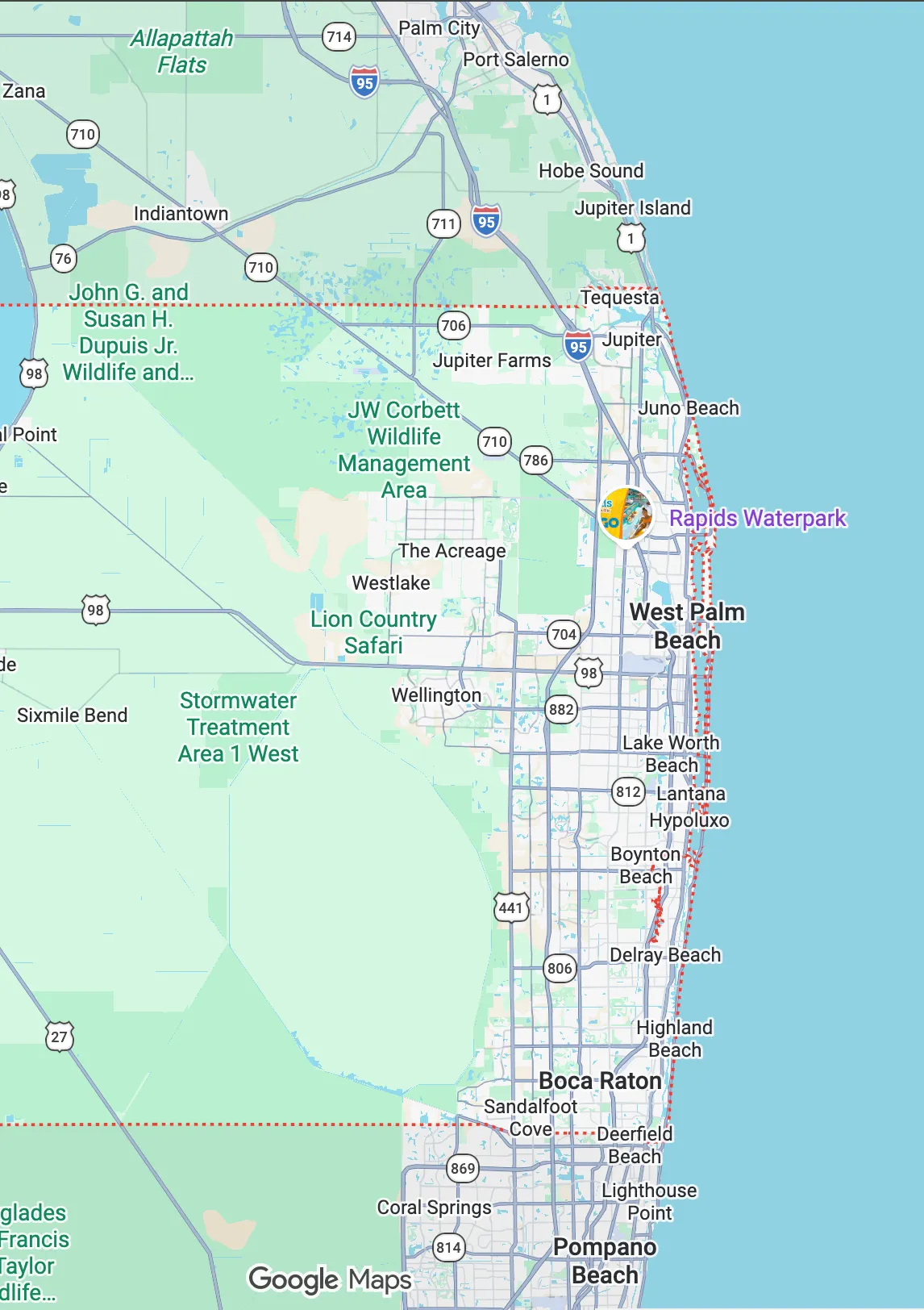 Smiling female doctor in white coat interacting with a young girl wearing hair clips and a pink sweater.