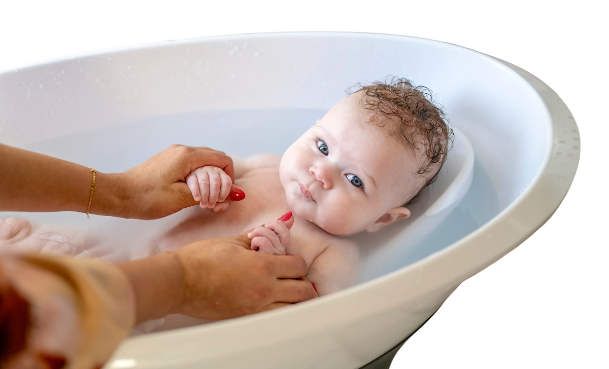 Smiling baby sitting in a white plastic baby bathtub.