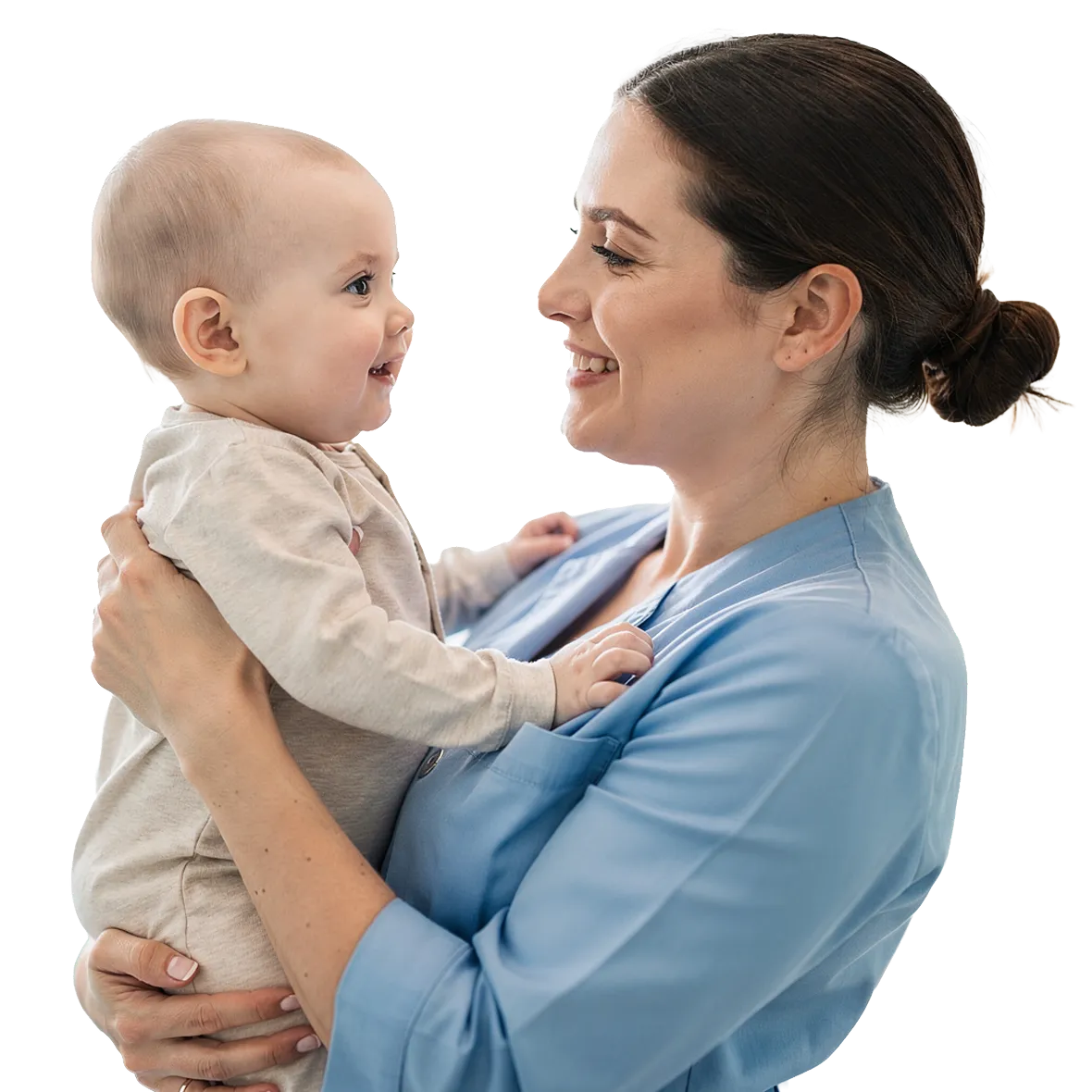 Female nurse in blue scrubs smiling and holding a happy baby facing her.