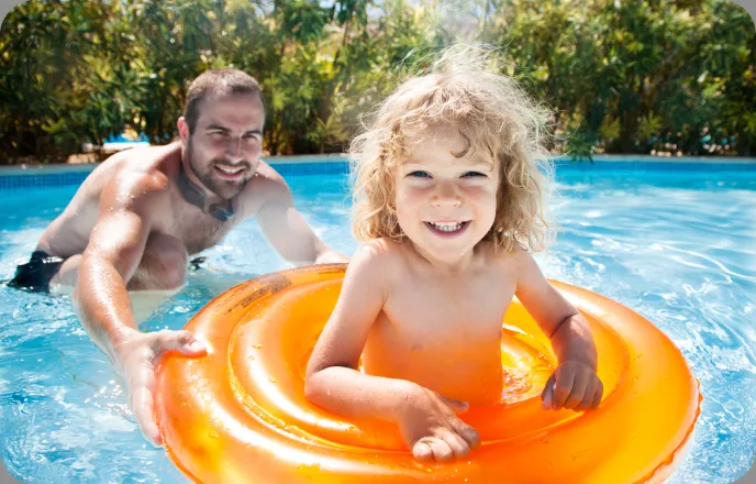 A father and son enjoying time together in a swimming pool.