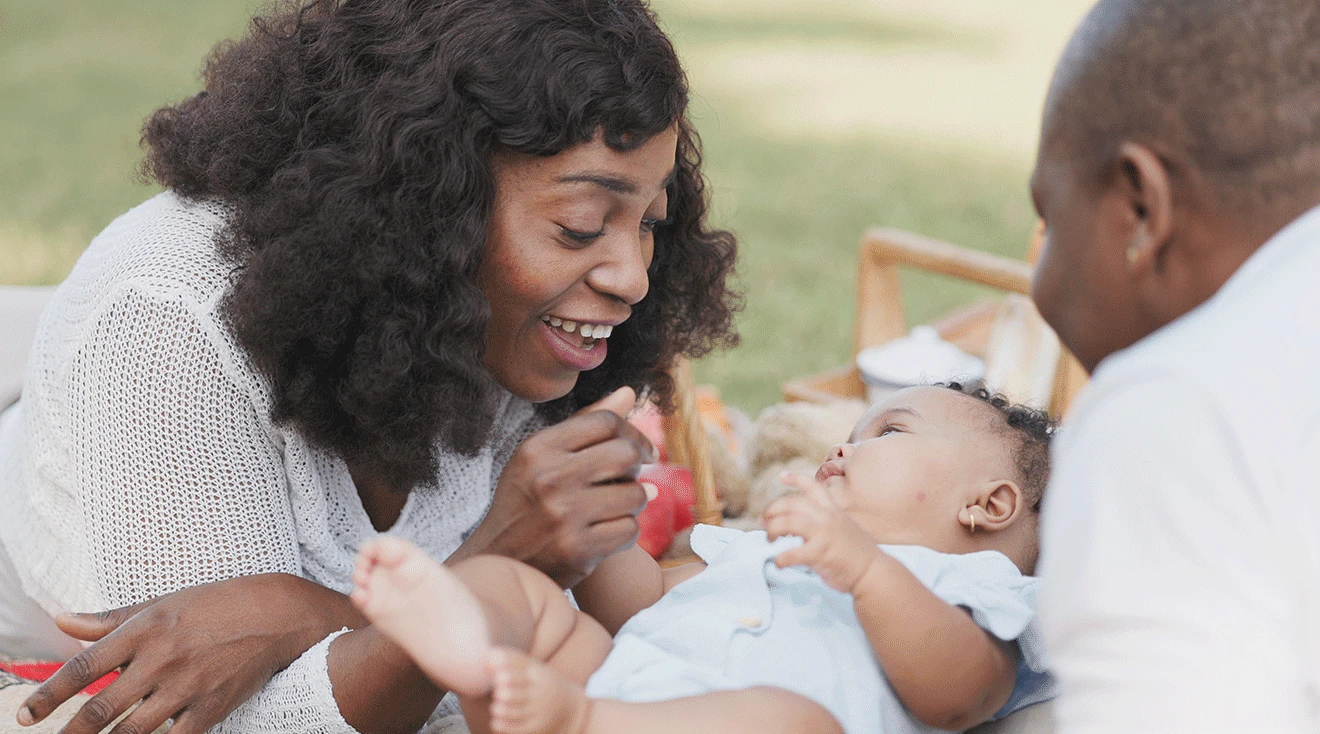 Parents smiling and playing with baby during outdoor picnic