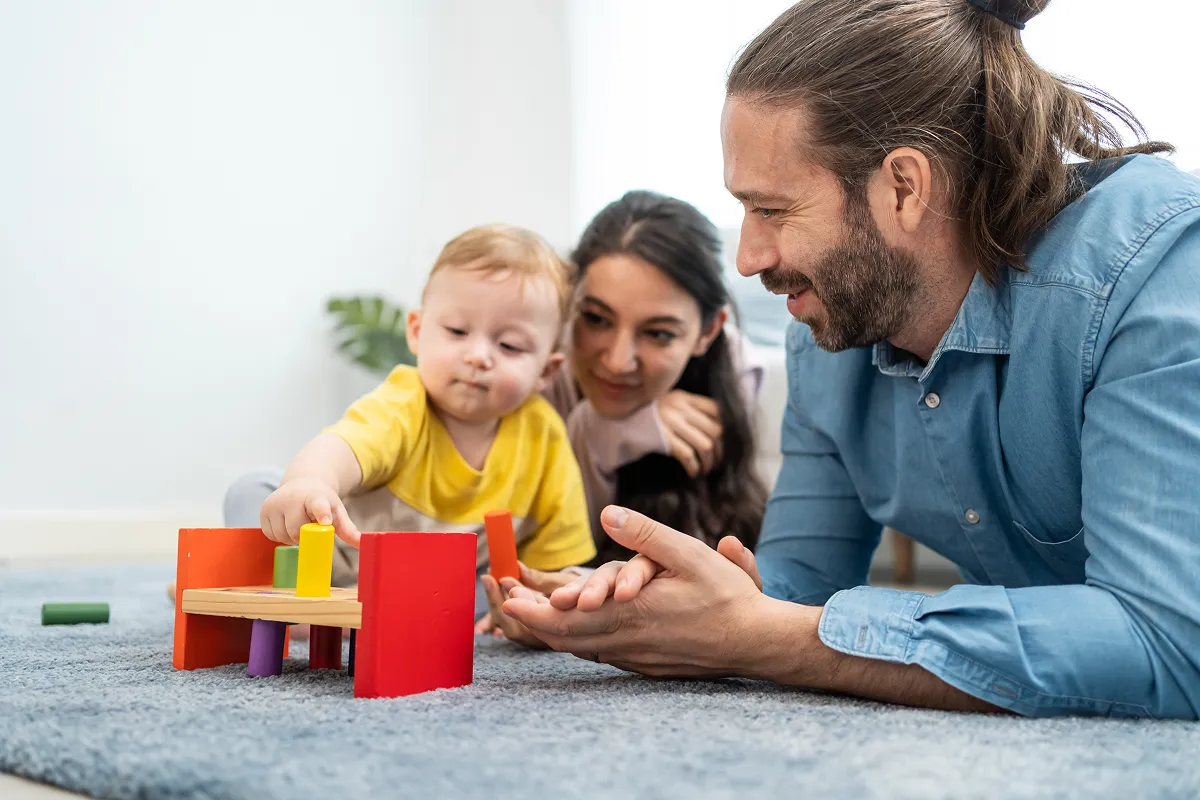 Parents smiling and playing with baby during outdoor picnic