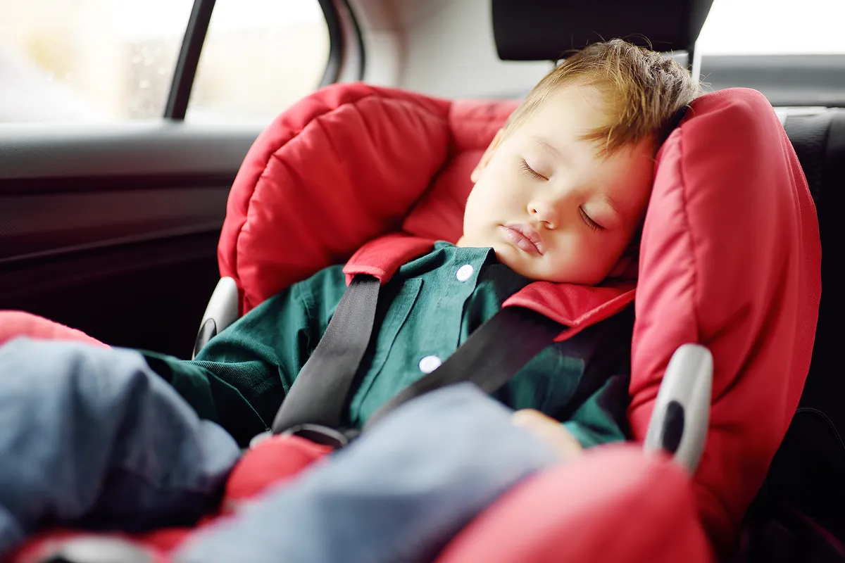 Cute toddler boy sleeping in car seat. Portrait of pretty little child during family road trip.
