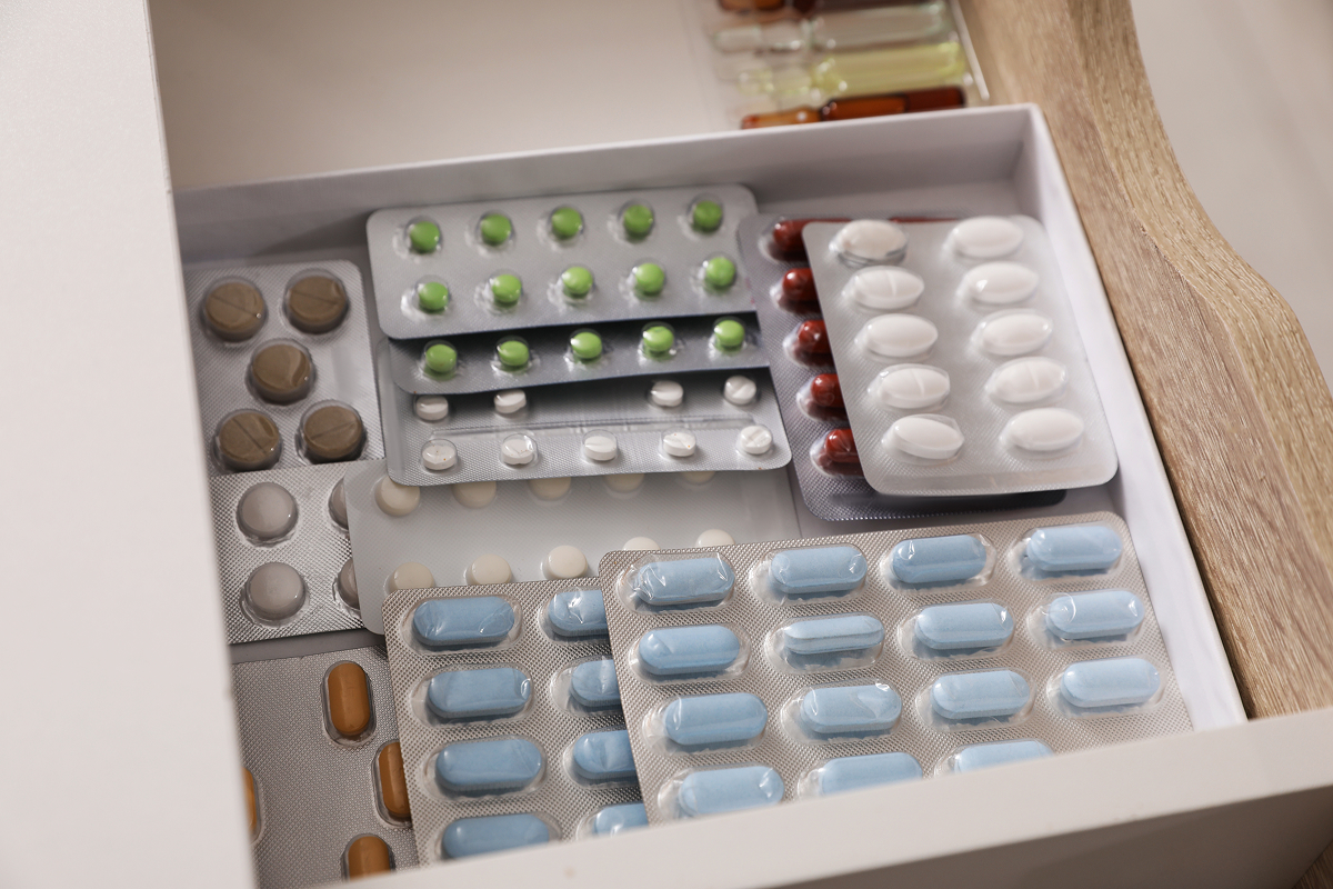 Open medicine drawer filled with blister packs of tablets and capsules