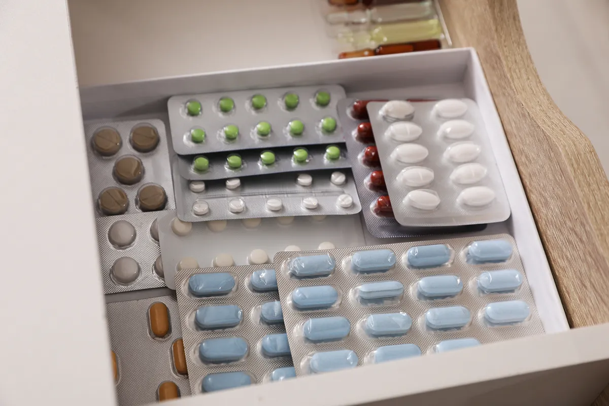 Open medicine drawer filled with blister packs of tablets and capsules