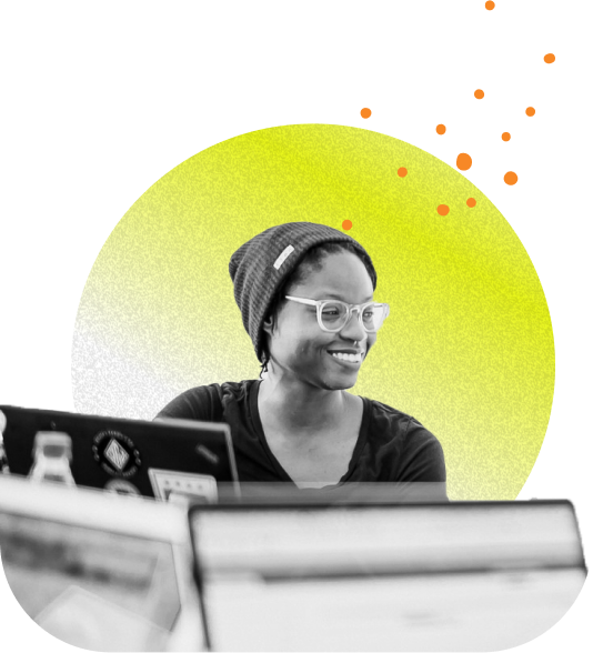 An engineer smiling in front of a few monitors with decorative elements in the background.