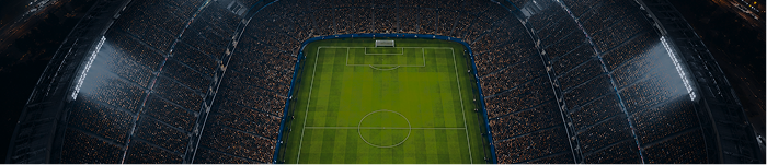 Vista aérea de un estadio de fútbol iluminado y lleno de espectadores por la noche.