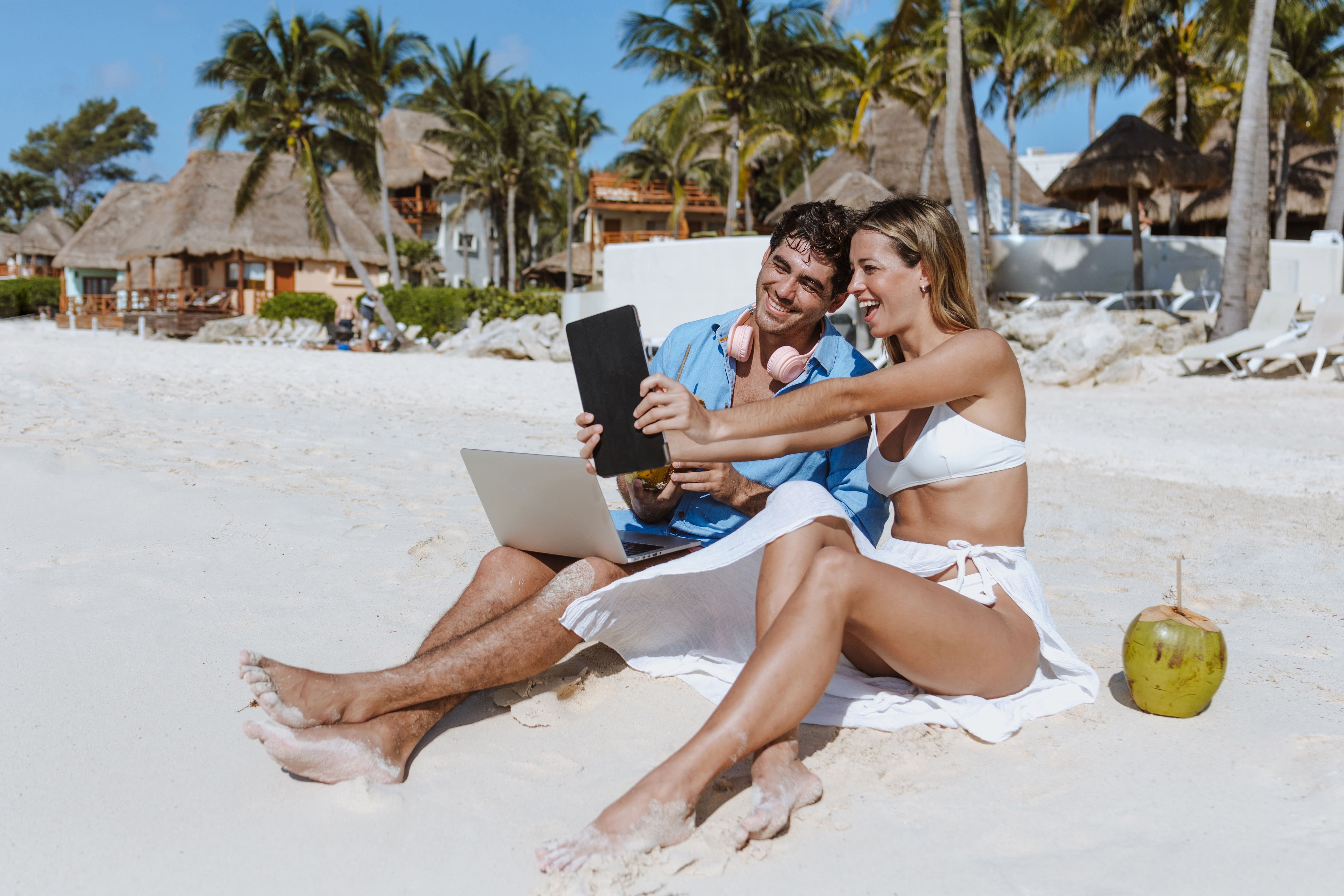 Digitale Nomaden arbeiten am Strand am Laptop mit einer Kokosnuss