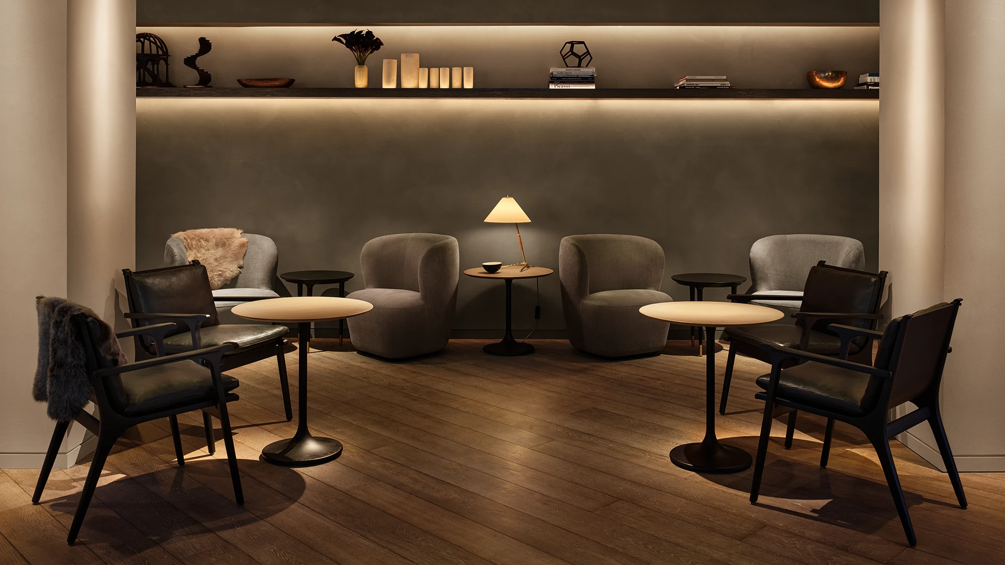 A concrete-walled lounge nook featuring four tables surrounded by bespoke seating