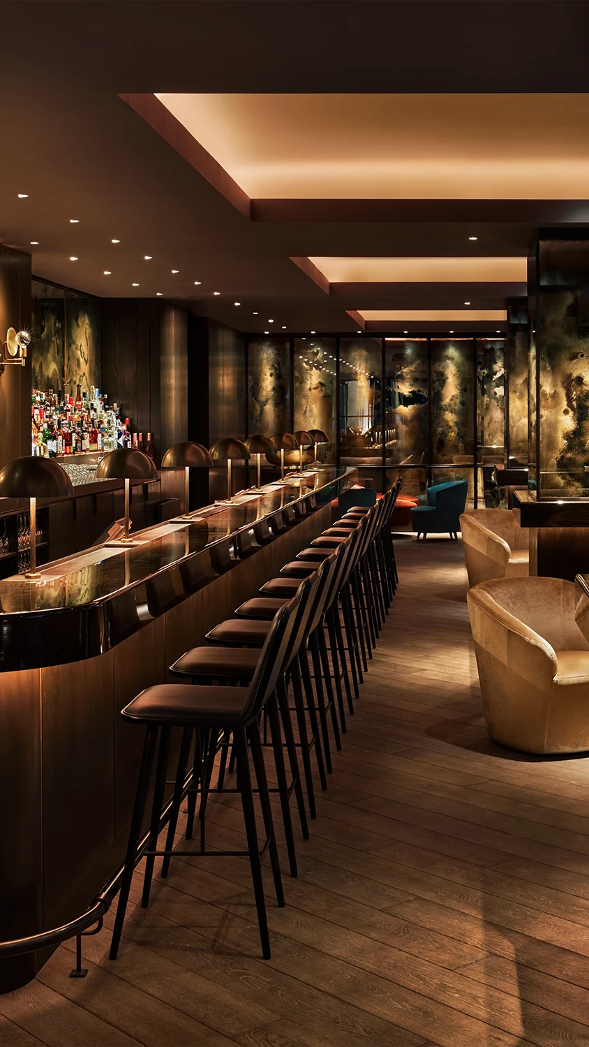 A hotel lounge bar lined with elegant chairs and a well-lit bar