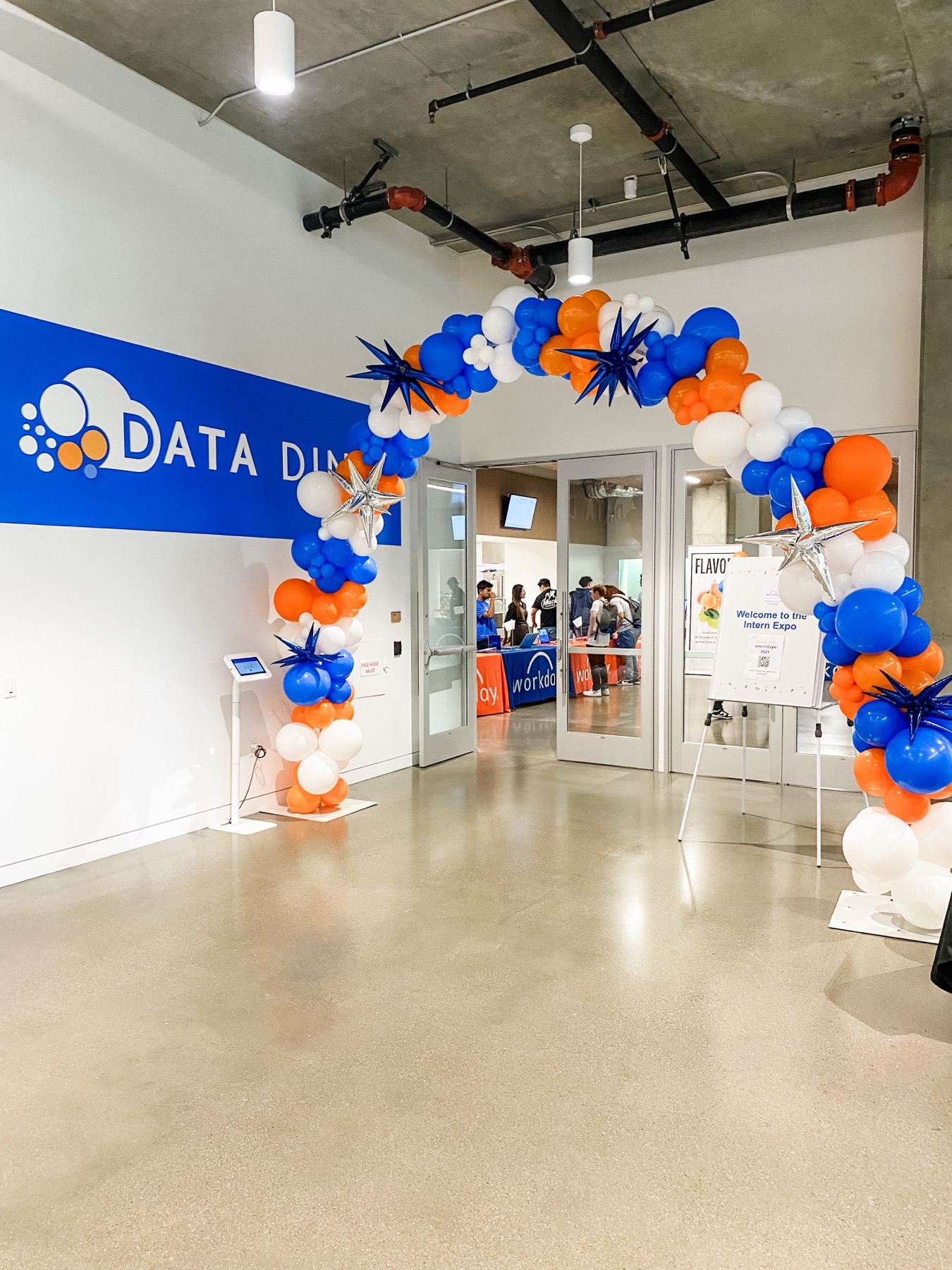 Corporate event entrance with a blue orange and white balloon arch by Poptastic Parties