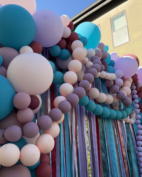 Side view of the finished squared balloon arch in Danville with lavender, blush and mauve balloon strands draped across the front of the ribbon curtain