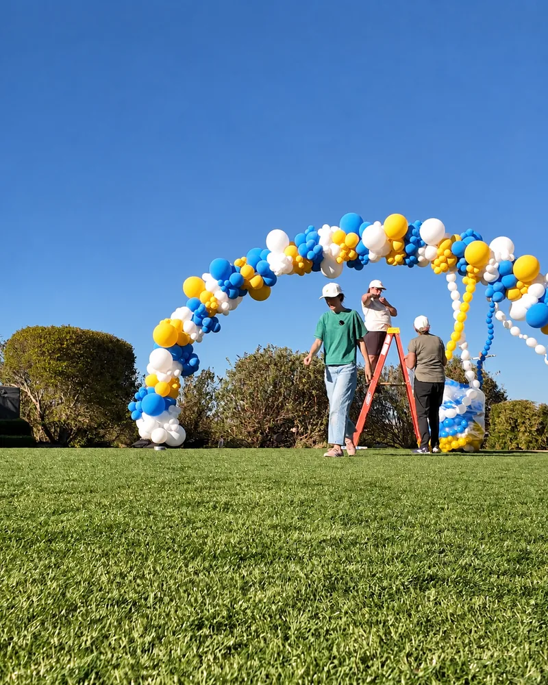 Three Poptastic Parties crew members and an orange ladder under the arch frame as the first link balloons start to go in